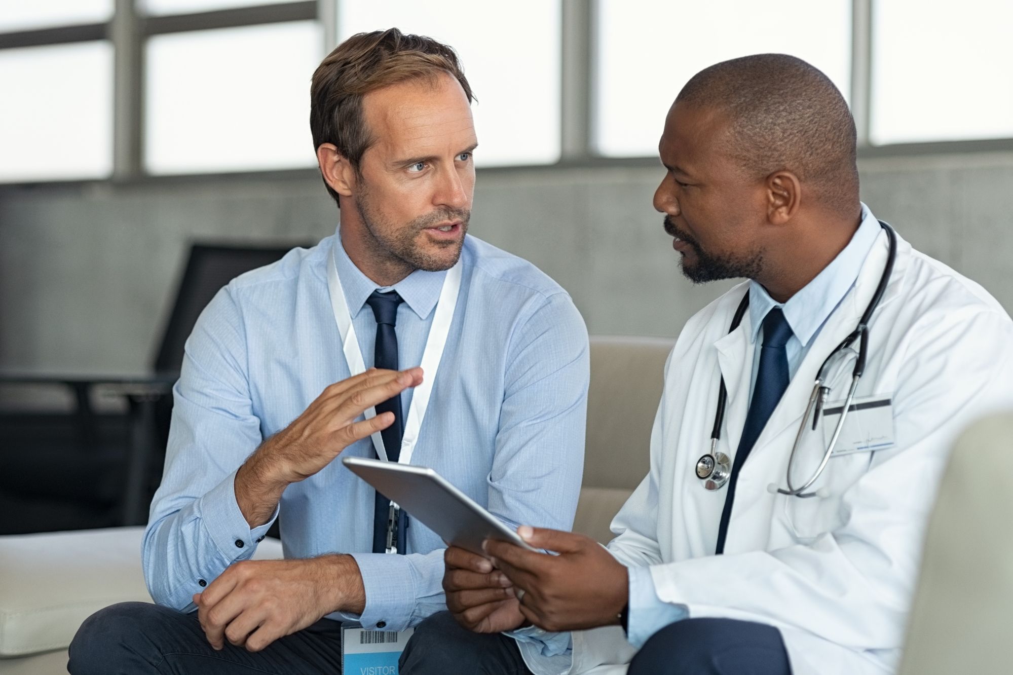 An auditor talking to a doctor in a white coat with a tablet in his hand